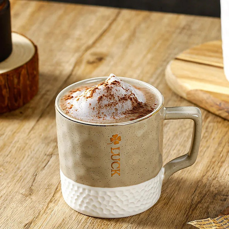 ماگ گلفی لاک رنگ کرم حاوی نوشیدنی روی میز چوبی از نمای رو به رو