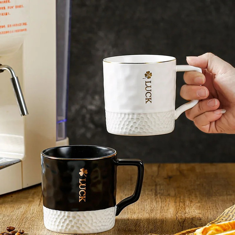 ماگ گلفی لاک رنگ مشکی روی میز چوبی و رنگ سفید در دست کاربر از نمای رو به رو