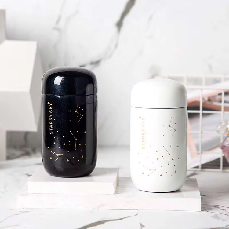 تراول ماگ ۲۰۰ میل Starry Sky در دو رنگ سفید مشکی در فضای اتاق روی میز سرامیکی