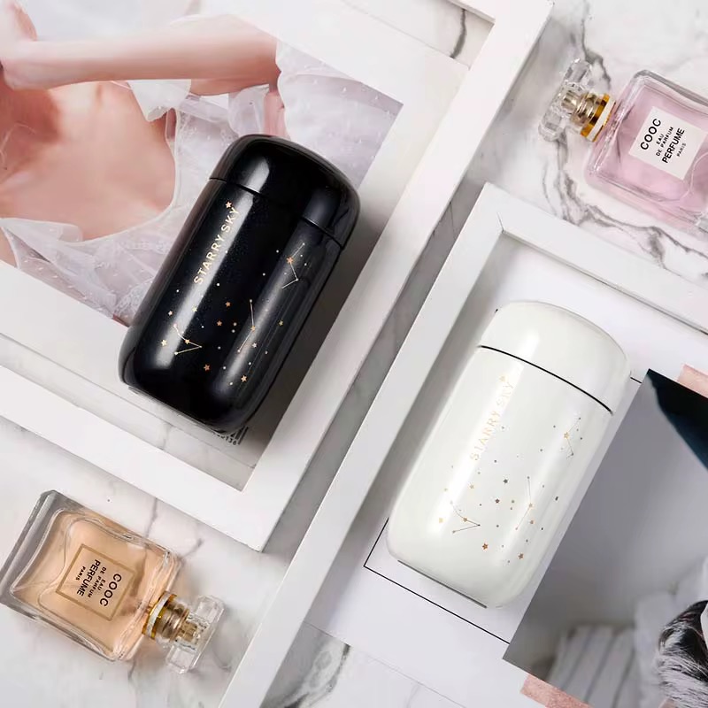 تراول ماگ ۲۰۰ میل Starry Sky در دو رنگ سفید مشکی داخل قاب روی میز با فضای دکوری