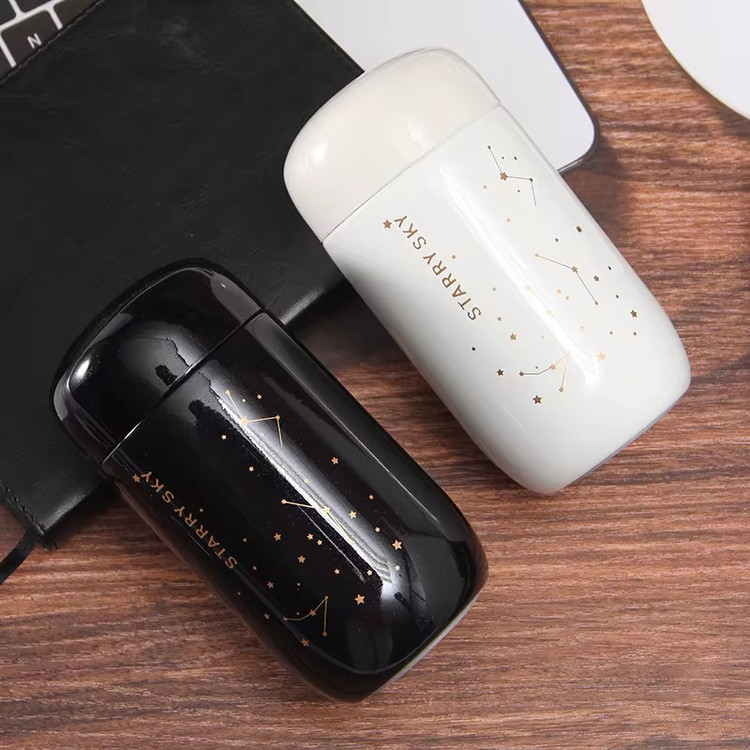 تراول ماگ ۲۰۰ میل Starry Sky در دو رنگ سفید مشکی روی میز چوبی